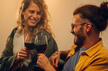 Happy couple clinking red wine glasses and enjoying their free time together.