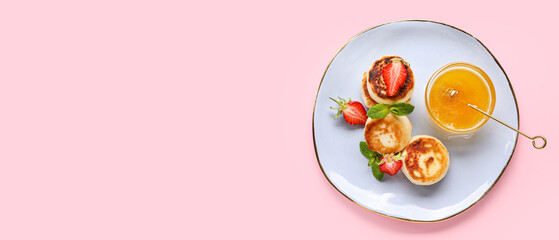 Plate with cottage cheese pancakes, strawberries and honey on pink background with space for text