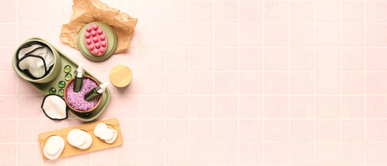 Set of bathing cosmetics and makeup pads on pink tile background with space for text