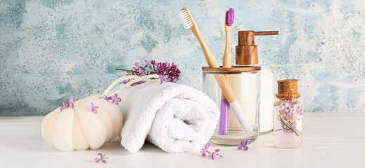 Bottles of liquid soap and serum, holder with bamboo tooth brushes, bast wisp and towel on blue...
