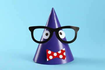 Handmade party hat with funny face on light blue background