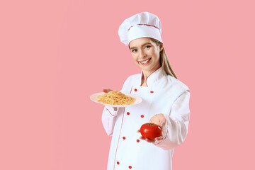 Female chef with tasty pasta and tomato on pink background