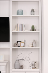 Stylish shelves with different decor elements in room. Interior design