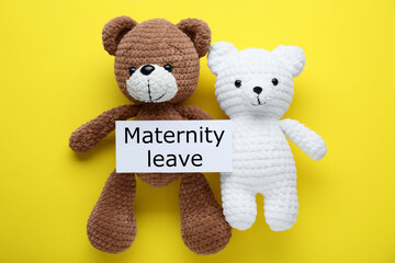 Toy bears and note with text Maternity Leave on yellow background, flat lay