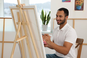 Fototapeta premium Young man painting in studio. Creative hobby