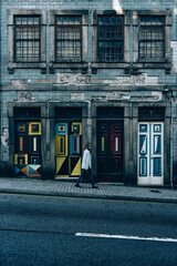 A woman walks in front of 4 colourful doors