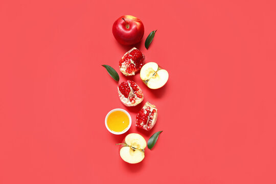 Composition with ripe apples, pomegranate and honey on red background. Rosh hashanah (Jewish New Year) celebration
