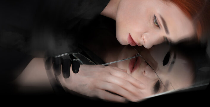 Suffering from hallucinations. Woman lying on broken mirror, demon in reflection touching her hand