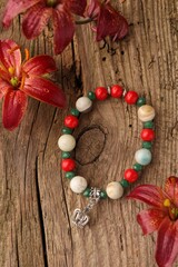 Beautiful bracelet with gemstones and lily flowers on wooden surface, flat lay