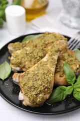 Delicious fried chicken drumsticks with pesto sauce and basil on white table, closeup