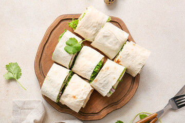 Wooden board of tasty lavash rolls with onion, egg and greens on light background