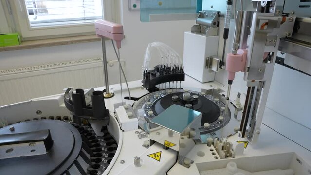 Blood samples with barcode slowly rotating and being scanned with barcode reader and laser on a laboratory analyzer in a small medical institution