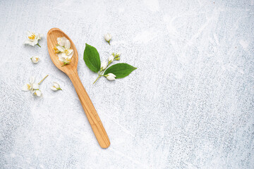 Wooden spoon with beautiful jasmine flowers on light background