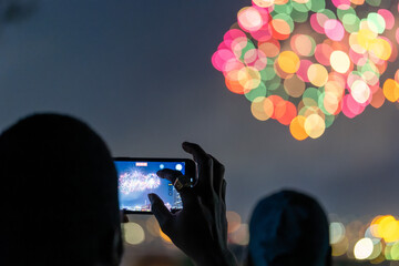 Man taking a cellphone video of fireworks on 4th of July - obrazy, fototapety, plakaty