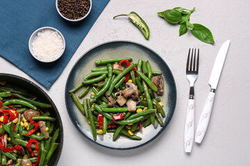Frying pan and plate with different vegetables on light background