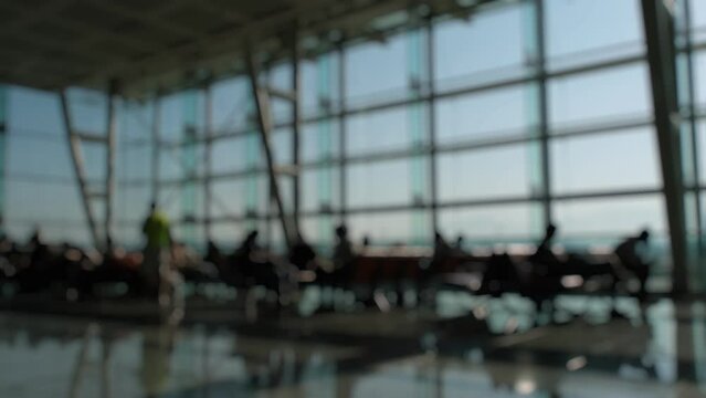Silhouettes of passengers waiting and walking in front of the boarding gates at Izmir Airport.