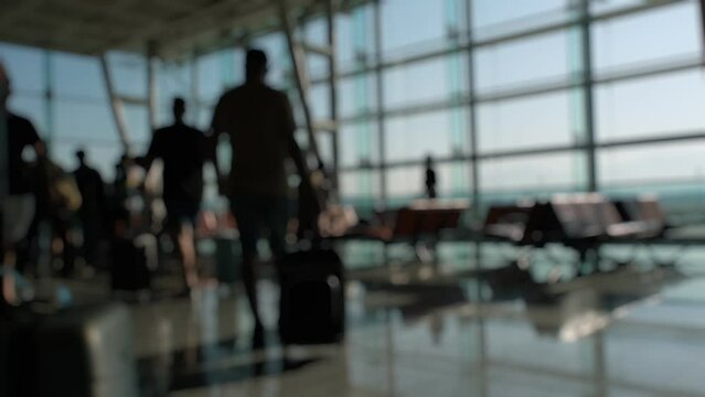 Silhouettes of passengers waiting and walking in front of the boarding gates at Izmir Airport.