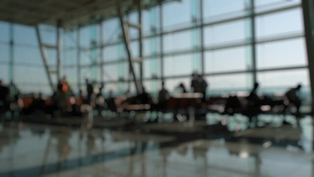 Silhouettes of passengers waiting and walking in front of the boarding gates at Izmir Airport.