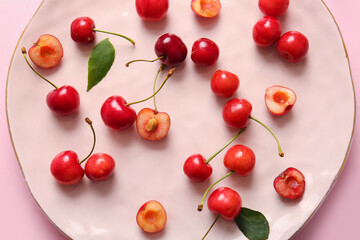 Naklejka na ściany i meble Plate with sweet cherries on pink background