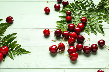 Naklejka na ściany i meble Many sweet cherries and leaves on green wooden background