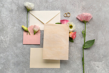 Composition with envelopes, blank cards, wedding rings and eustoma flowers on grey background