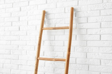 Wooden ladder near white brick wall in room