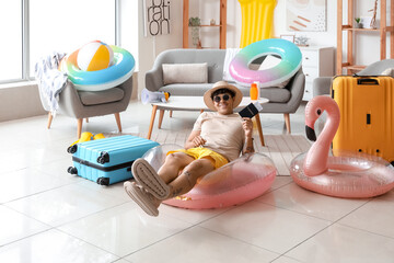 Young man with passport and beach accessories ready for summer vacation at home