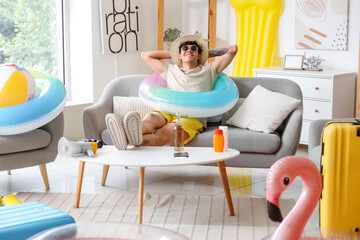 Young man with beach accessories ready for summer vacation at home