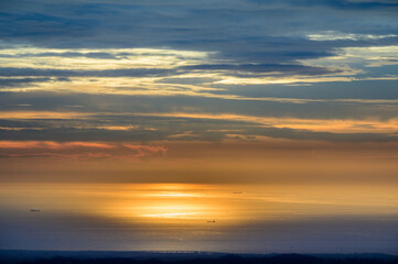 The sky and sea are orange and gold. Ships and dynamic clouds. At dusk, the scenery of the seaside in Miaoli County.
