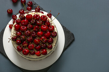 Board with tasty cherry cake on dark background