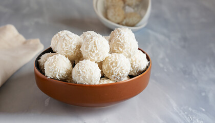 Coconut balls, raw and healthy sugar free rafaello candies. Vegetarian energy sweets recipe step by step. Round tasty dessert in ceramic bowl. Copy space, close up view. Healthy organic food for kids.
