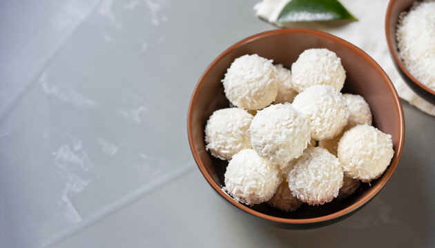 Coconut balls, raw and healthy sugar free rafaello candies. Vegetarian energy sweets recipe step by step. Round tasty dessert in ceramic bowl. Copy space, close up view. Healthy organic food for kids.