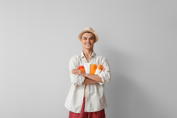 Happy young man with different bottles of sunscreen cream on grey background