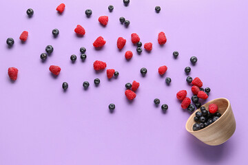 Bowl with fresh blueberries and raspberries on lilac background