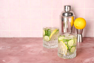 Glasses of mojito with cucumber on grunge pink table