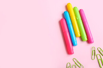 Markers and paper clips in shape of rocket on pink background