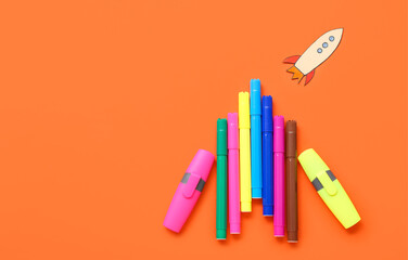 Markers with paper rocket on red background