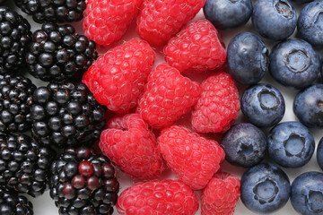 Fresh raspberry, blackberry and blueberry on light background, closeup
