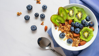 Yogurt bowl with homemade granola (muesli), nuts, fresh berries (blueberry) and kiwi fruit. Healthy eating. Tasty and easy cooking summer breakfast or snack. Top view, copy space, white background.