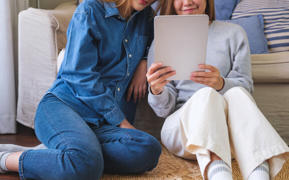 Closeup image of a young couple women holding and using digital tablet together