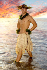 A hot masculine hula dancer poses in the sea at sunset in Hawaii.