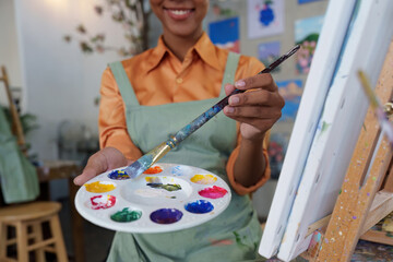 Beautiful american african artist woman painting in art studio at the university classroom