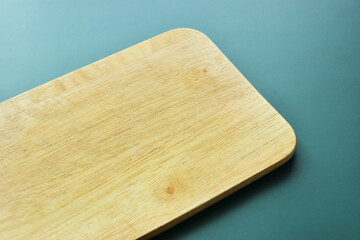 brown wooden cutting board on green background, equipment for cooking in the kitchen