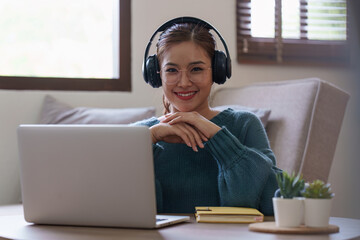 Young asian relaxed smiling pretty woman relaxing with laptop at home. Female feeling joy enjoying with mobile phone on cozy couch