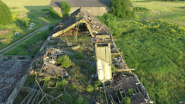 Koeru.Estonia-July 5.2021: Aerial shot of a ruined soviet farm building showing the old structure slowly decaying and becoming one with nature. Drone slowly moving backwards.