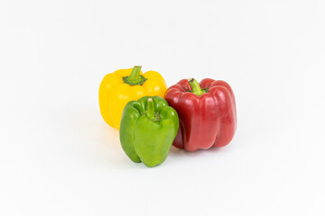 Green, yellow and red bell peppers on white background.