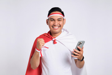 Excited young Asian men celebrate Indonesian independence day on 17 August while holding mobile phone isolated over white background
