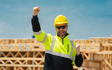 Excited foreman in hard hat at new house under construction. Builder on construction site....