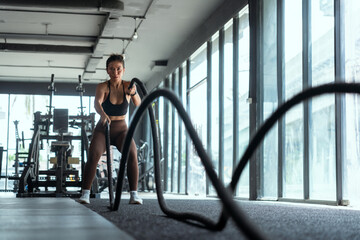 Fototapeta na wymiar Woman with battle rope battle ropes exercise in the fitness gym. gym, sport, rope, training, athlete, workout, exercises concept