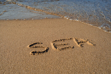 Text SEA handwritten in sand surface. Blue ocean wave washing away message at the beach. Summer holidays beach writing vacation concept